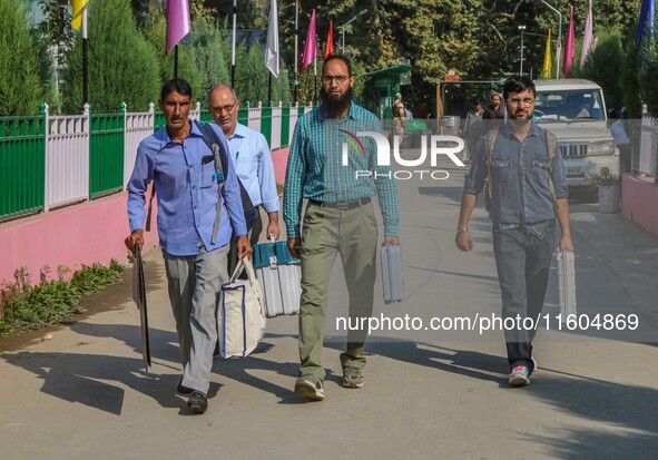 Polling officials carry electronic voting machines (EVM) at a distribution center in Srinagar, Jammu and Kashmir, on September 24, 2024, on...