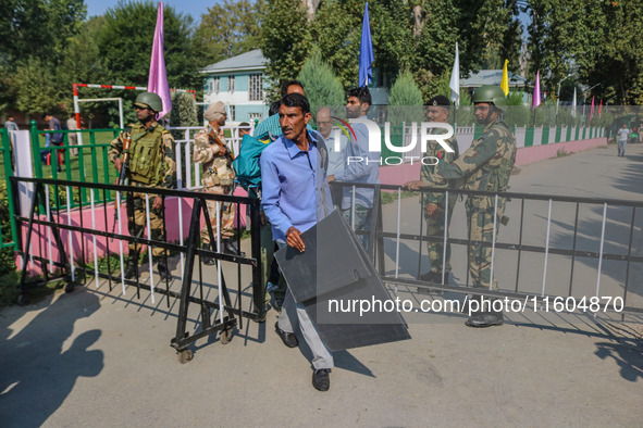 Polling officials carry electronic voting machines (EVM) at a distribution center in Srinagar, Jammu and Kashmir, on September 24, 2024, on...