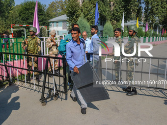 Polling officials carry electronic voting machines (EVM) at a distribution center in Srinagar, Jammu and Kashmir, on September 24, 2024, on...