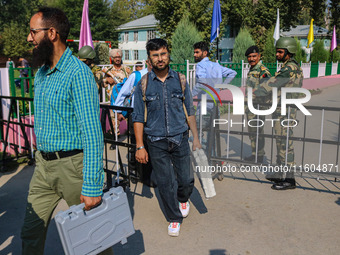 Polling officials carry electronic voting machines (EVM) at a distribution center in Srinagar, Jammu and Kashmir, on September 24, 2024, on...