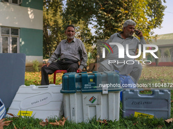 Polling officials sit beside electronic voting machines (EVM) at a distribution center on the eve of the second phase of voting during assem...