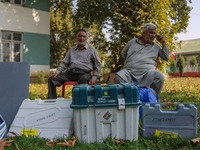 Polling officials sit beside electronic voting machines (EVM) at a distribution center on the eve of the second phase of voting during assem...