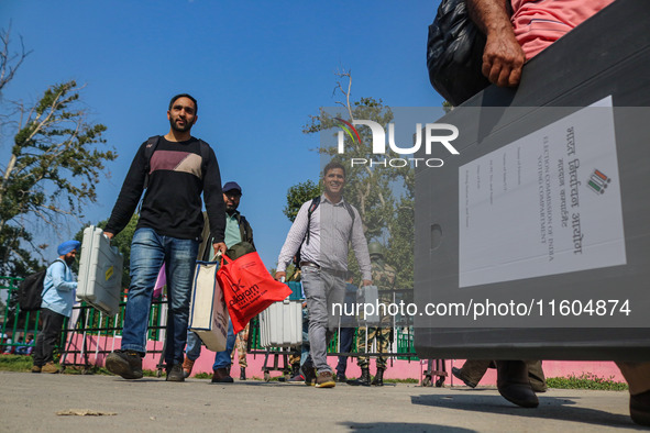 Polling officials carry electronic voting machines (EVM) at a distribution center in Srinagar, Jammu and Kashmir, on September 24, 2024, on...