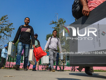 Polling officials carry electronic voting machines (EVM) at a distribution center in Srinagar, Jammu and Kashmir, on September 24, 2024, on...