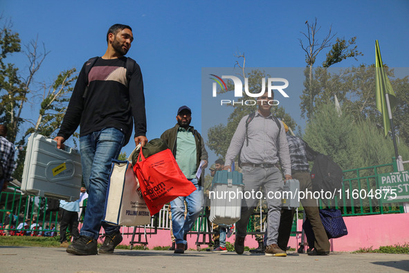 Polling officials carry electronic voting machines (EVM) at a distribution center in Srinagar, Jammu and Kashmir, on September 24, 2024, on...