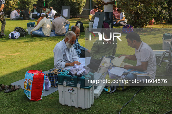 Polling officials sit beside electronic voting machines (EVM) at a distribution center on the eve of the second phase of voting during assem...