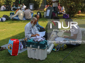 Polling officials sit beside electronic voting machines (EVM) at a distribution center on the eve of the second phase of voting during assem...