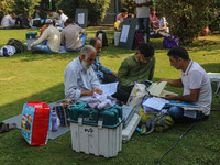 Polling officials sit beside electronic voting machines (EVM) at a distribution center on the eve of the second phase of voting during assem...