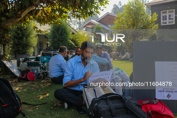 Polling officials sit beside electronic voting machines (EVM) at a distribution center on the eve of the second phase of voting during assem...