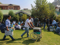 Polling officials with electronic voting machines (EVM) gather at a distribution center on the eve of the second phase of voting during asse...