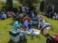 Polling officials with electronic voting machines (EVM) gather at a distribution center on the eve of the second phase of voting during asse...