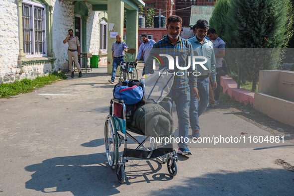 Polling officials carry electronic voting machines (EVM) at a distribution center in Srinagar, Jammu and Kashmir, on September 24, 2024, on...