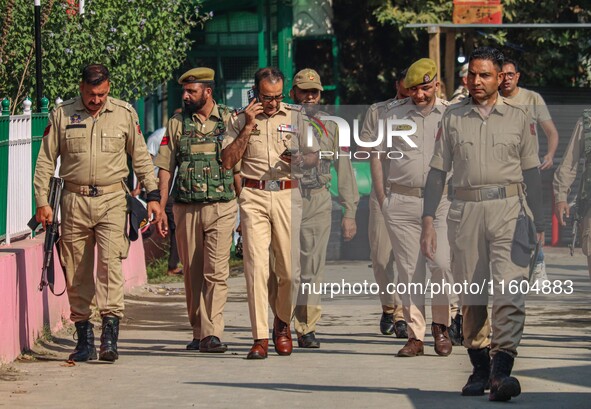 Indian policemen patrol as polling officials carry electronic voting machines (EVM) at a distribution center in Srinagar, Jammu and Kashmir,...