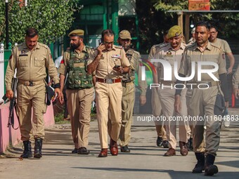 Indian policemen patrol as polling officials carry electronic voting machines (EVM) at a distribution center in Srinagar, Jammu and Kashmir,...