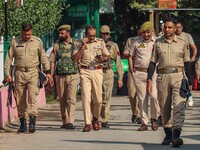 Indian policemen patrol as polling officials carry electronic voting machines (EVM) at a distribution center in Srinagar, Jammu and Kashmir,...