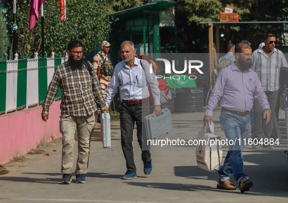 Polling officials carry electronic voting machines (EVM) at a distribution center in Srinagar, Jammu and Kashmir, on September 24, 2024, on...