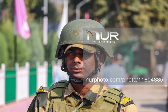 An Indian security personnel stands guard as polling officials carry electronic voting machines (EVM) at a distribution center on the eve of...