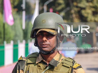 An Indian security personnel stands guard as polling officials carry electronic voting machines (EVM) at a distribution center on the eve of...