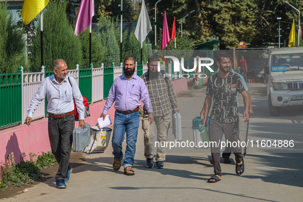 Polling officials carry electronic voting machines (EVM) at a distribution center in Srinagar, Jammu and Kashmir, on September 24, 2024, on...