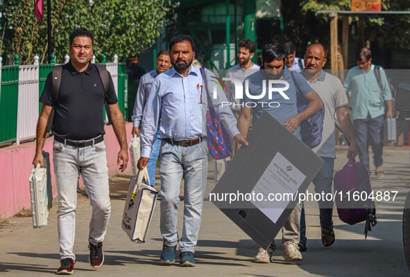 Polling officials carry electronic voting machines (EVM) at a distribution center in Srinagar, Jammu and Kashmir, on September 24, 2024, on...