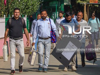 Polling officials carry electronic voting machines (EVM) at a distribution center in Srinagar, Jammu and Kashmir, on September 24, 2024, on...