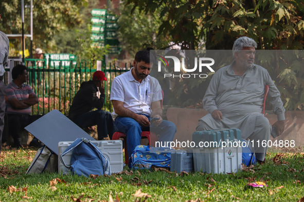 Polling officials sit beside electronic voting machines (EVM) at a distribution center on the eve of the second phase of voting during assem...