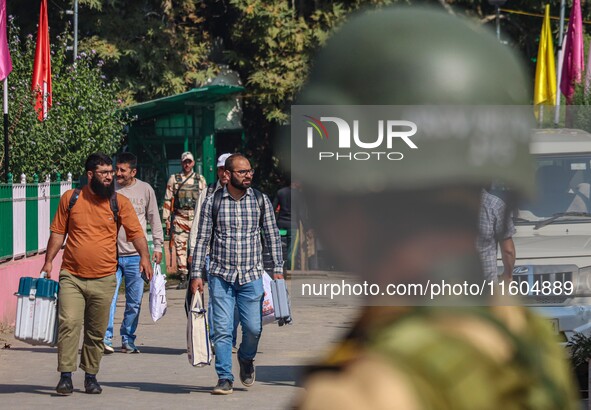 An Indian security personnel stands guard as polling officials carry electronic voting machines (EVM) at a distribution center on the eve of...