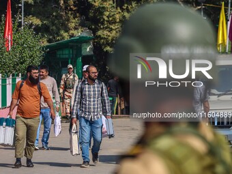 An Indian security personnel stands guard as polling officials carry electronic voting machines (EVM) at a distribution center on the eve of...