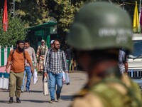 An Indian security personnel stands guard as polling officials carry electronic voting machines (EVM) at a distribution center on the eve of...