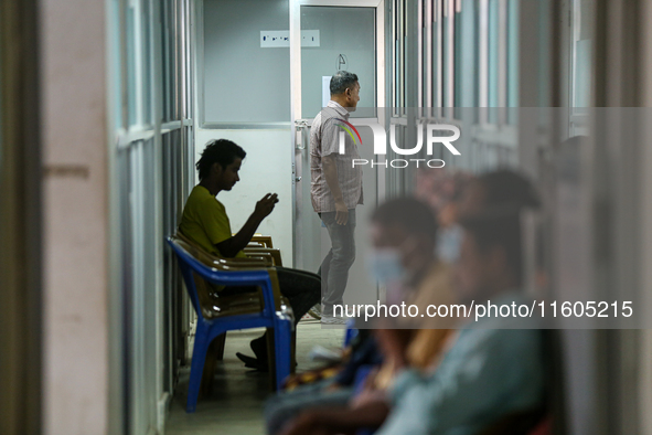 An infected patient uses a mobile phone as he waits for his turn at the Fever Clinic of Sukraraj Tropical and Infectious Disease Hospital in...