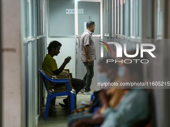 An infected patient uses a mobile phone as he waits for his turn at the Fever Clinic of Sukraraj Tropical and Infectious Disease Hospital in...