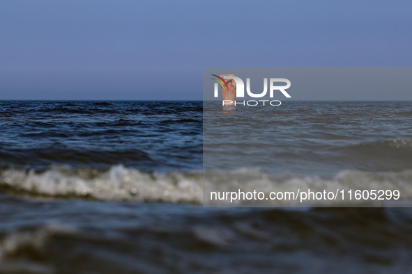 A tourist is seen taking a bath in Autumn cold water of Baltic Sea on a sand beach near Leba, famous pomeranian tourist resort in northern P...