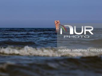 A tourist is seen taking a bath in Autumn cold water of Baltic Sea on a sand beach near Leba, famous pomeranian tourist resort in northern P...