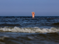 A tourist is seen taking a bath in Autumn cold water of Baltic Sea on a sand beach near Leba, famous pomeranian tourist resort in northern P...