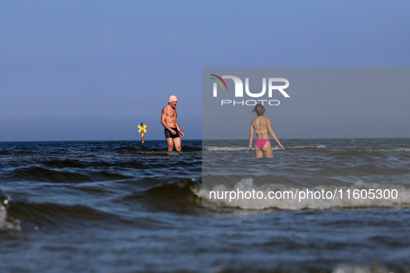 A tourist is seen taking a bath in Autumn cold water of Baltic Sea on a sand beach near Leba, famous pomeranian tourist resort in northern P...