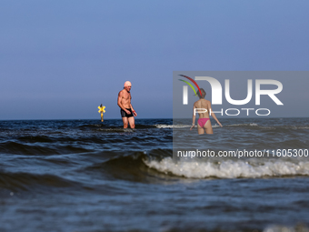 A tourist is seen taking a bath in Autumn cold water of Baltic Sea on a sand beach near Leba, famous pomeranian tourist resort in northern P...