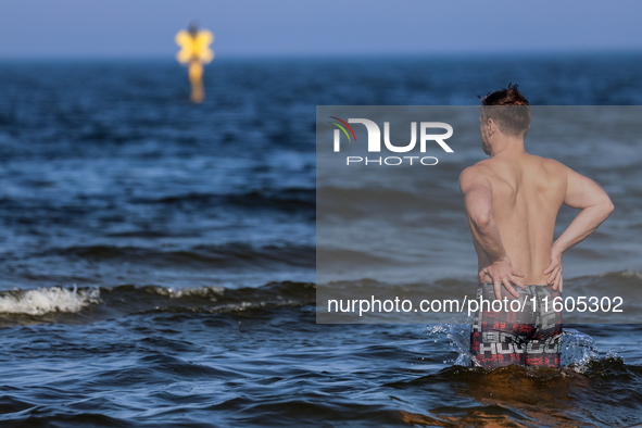 A tourist is seen taking a bath in Autumn cold water of Baltic Sea on a sand beach near Leba, famous pomeranian tourist resort in northern P...