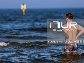 A tourist is seen taking a bath in Autumn cold water of Baltic Sea on a sand beach near Leba, famous pomeranian tourist resort in northern P...