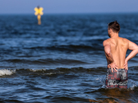 A tourist is seen taking a bath in Autumn cold water of Baltic Sea on a sand beach near Leba, famous pomeranian tourist resort in northern P...