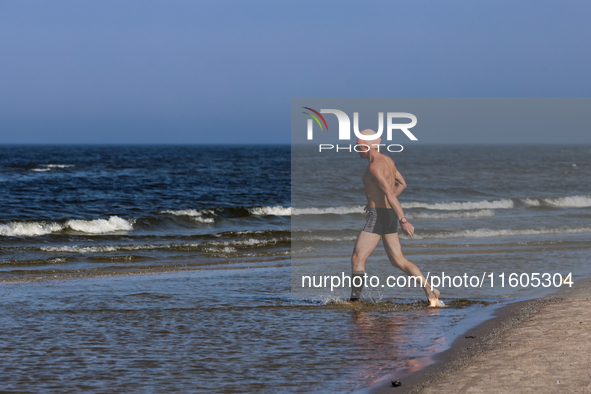 A tourist is seen taking a bath in Autumn cold water of Baltic Sea on a sand beach near Leba, famous pomeranian tourist resort in northern P...