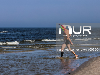 A tourist is seen taking a bath in Autumn cold water of Baltic Sea on a sand beach near Leba, famous pomeranian tourist resort in northern P...