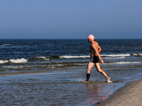 A tourist is seen taking a bath in Autumn cold water of Baltic Sea on a sand beach near Leba, famous pomeranian tourist resort in northern P...