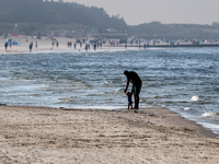 A father teaches a toddler to walk on a beach late in the afternoon as the sun sets on a sand beach by Baltic Sea near Leba, famous pomerani...