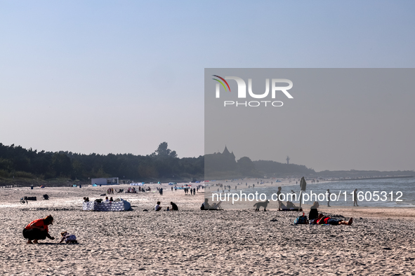 Tourists rest on a beach late in the afternoon as the sun sets on a sand beach by Baltic Sea near Leba, famous pomeranian tourist resort in...