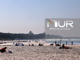 Tourists rest on a beach late in the afternoon as the sun sets on a sand beach by Baltic Sea near Leba, famous pomeranian tourist resort in...