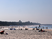 Tourists rest on a beach late in the afternoon as the sun sets on a sand beach by Baltic Sea near Leba, famous pomeranian tourist resort in...