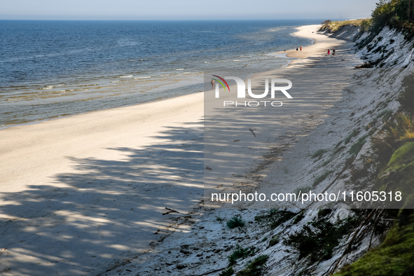 Tourists are seen walking on a beach late in the afternoon as the sun sets on a sand beach by Baltic Sea near Leba, famous pomeranian touris...