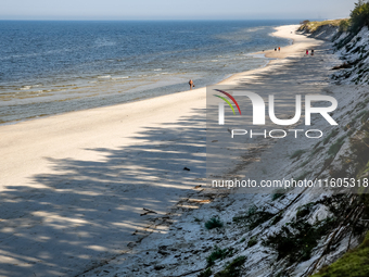 Tourists are seen walking on a beach late in the afternoon as the sun sets on a sand beach by Baltic Sea near Leba, famous pomeranian touris...