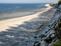 Tourists are seen walking on a beach late in the afternoon as the sun sets on a sand beach by Baltic Sea near Leba, famous pomeranian touris...