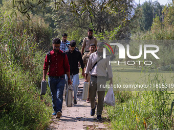 Polling officials along with Indian policemen walk in the interiors of Dal Lake towards their designated polling station after collecting el...